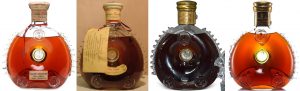 Four Louis XIII bottles of Rémy Martin: first two are white tops with different labels, last two are gold tops with different necks (see embossed letters on third bottle's neck)