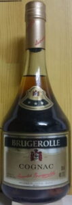 Low bottle, clear glass, longer capsule; signature in red, also a signature on the capsule